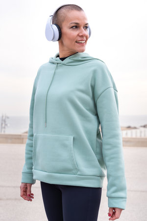 Vertical Portrait smiling sporty woman with headphones looking at the camera outdoors.
