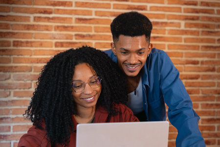 Happy multiethnic man and woman have fun browsing internet on laptop.