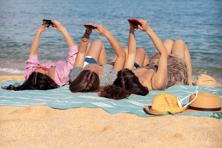 Young women taking pictures sunbathingの写真素材