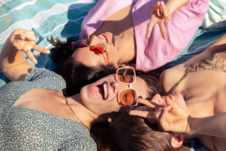 Three young women sunbathing on beach towels on the sandの写真素材