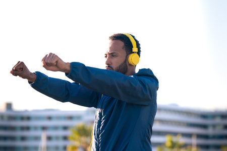 Active and fit male runner in warm-up stretch for running or cardio exercise.