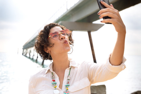 Happy woman takes a selfie together with smartphone on the beach
