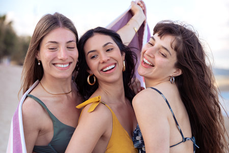 Portrait of three female friends looking at camera on the beach having fun.