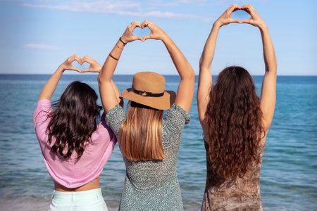 Portrait of two female friends looking at camera on the beach having fun.