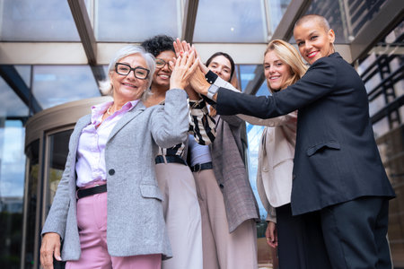 Group of five smiling businesswomen outdoors.