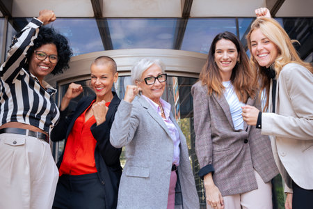 Group of five smiling businesswomen with hands up outdoors.の写真素材