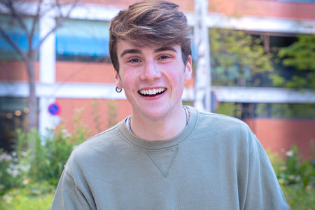 Portrait of close young man quite smiling looking happily in the chamber outdoor