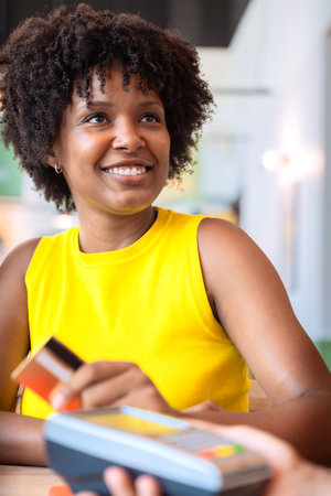 Smiling customer paying with contactless credit card in a restaurant .Vertical