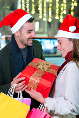 Excited Couple Exchanging Christmas Gifts Outdoors.Verticalの写真素材