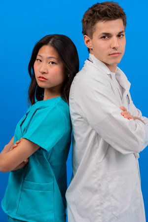 Serious Medical Professionals Standing Back-to-Back on Blue Background.Verticalの写真素材