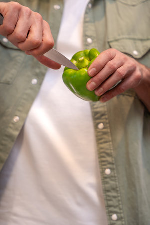 Unrecognizable man Slicing a Green Bell Pepper with Precision.Vertical