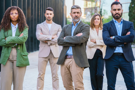 Group of business professionals standing together with arms crossed outdoors