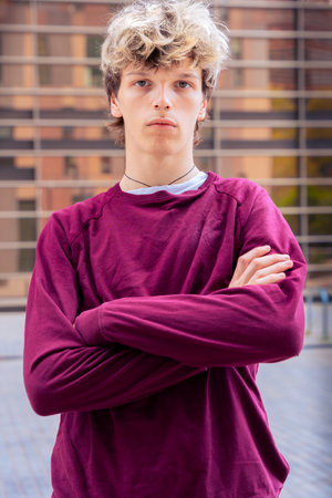 Vertical portrait Serious Teenage Boy with Arms Crossed in Urban Environmentの写真素材