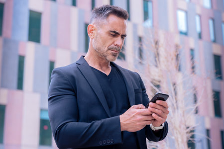 Confident businessman using smartphone outdoors,