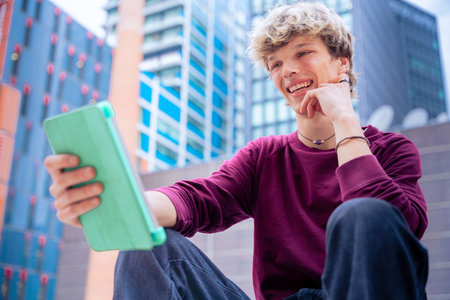 Smiling Teenage Boy Using Tablet in Modern Urban Setting,copy spaceの写真素材