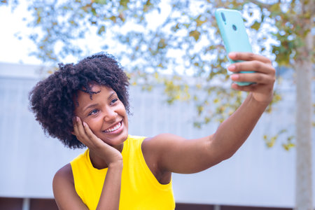African american Smiling young woman taking a selfie with smartphone in urban settingの写真素材