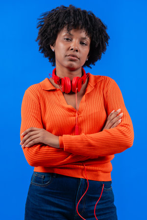 Serious african American woman with red headphones posing against blue backgroundの写真素材