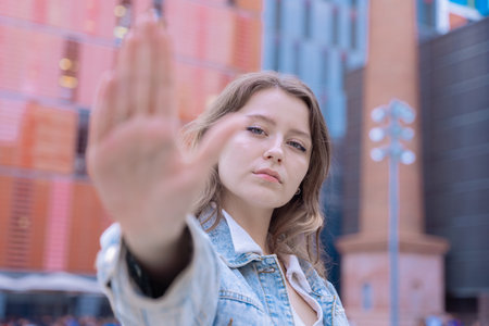 Serious young woman making stop gesture with hand in modern urban setting.の写真素材