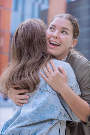 Happy Caucasian friends hugging and smiling outdoors in an urban environmentの写真素材