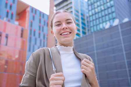 Happy Caucasian young woman looking at camera and smiling in urban setting