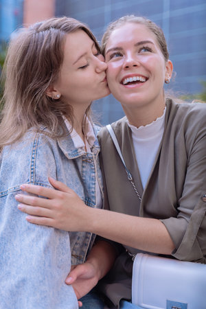 Happy Caucasian friends showing affection with a kiss on the cheek outdoorsの写真素材