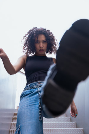 African American woman dancing outdoors between benches in urban modern space
