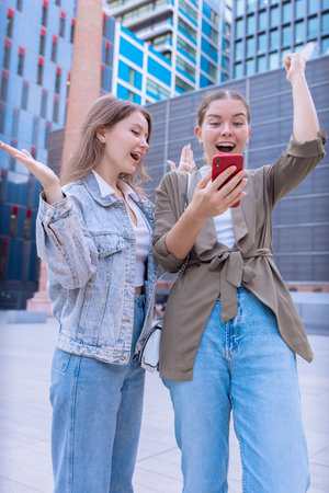 Caucasian women celebrating outdoors with smartphoneの写真素材