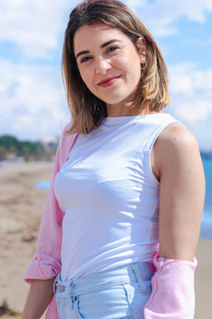 Close-up portrait of young woman on beach vacation smiling and looking at camera