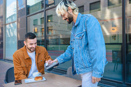 Man paying with card at outdoor cafe while friend smiles, casual urban setting