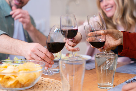 Group of multicultural friends making a toast with red wine glasses during a festive dinnerの写真素材