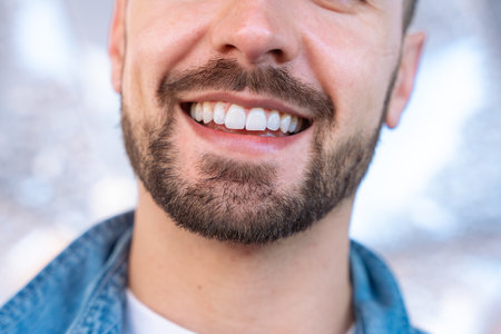 Close-up of smiling mans face with perfect white teeth and trimmed beardの写真素材