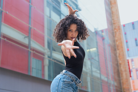 African American woman dancing outdoors between benches in urban modern spaceの写真素材