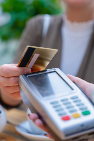 Close-up of contactless credit card payment at cafe with point of sale terminal