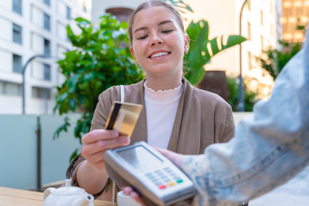 Caucasian woman smiling while making contactless credit card payment at cafeの写真素材