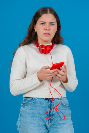 Frustrated woman holding red smartphone with confused expression on her faceの写真素材
