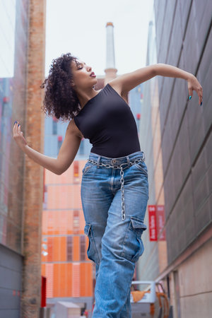 African American woman dancing outdoors between benches in urban modern spaceの写真素材
