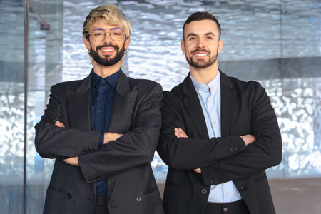 Two confident businessmen standing with arms crossed and smiling at cameraの写真素材