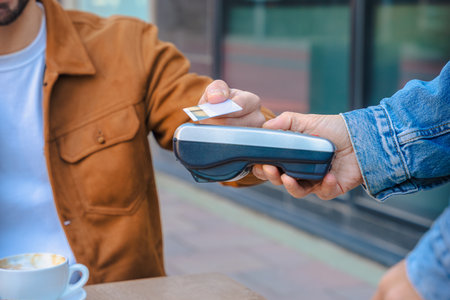 Contactless card payment with POS terminal in cafe, hands close up, modern scene