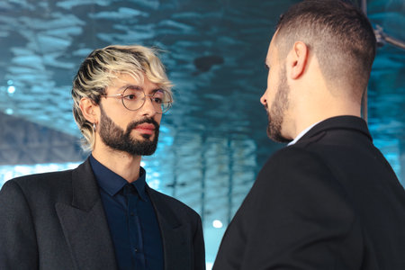 Two businessmen talking seriously inside a modern office with glass background