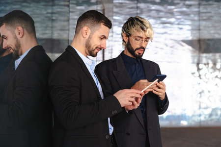 Two businessmen in suits working with digital tablets in modern glass officeの写真素材