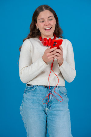 Vertical Portrait of Happy Woman Listening to Music on Phone with Red Headphones