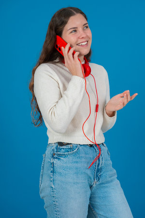 Vertical portrait of joyful woman talking on red smartphone with headphonesの写真素材