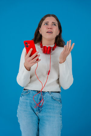 Worried woman reading bad news on smartphone with shocked expression and blue background