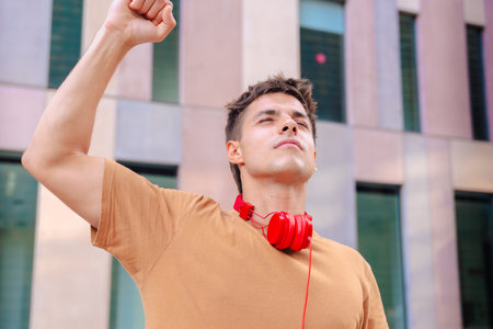 Young man raising fist in the air outdoors with determined expression