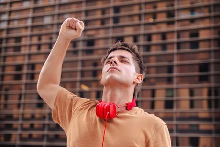 Young man raising fist in the air outdoors with determined expressionの写真素材