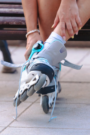 Vertical close up unrecognizable person adjusting inline rollerblade outdoor