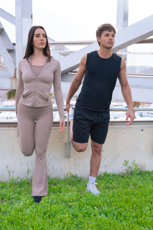 Man training with resistance band outdoors while woman walksの写真素材