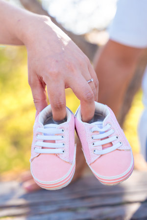 Unrecognizable couple holding pink baby shoes, symbol of love, hope, new life.Verticalの写真素材