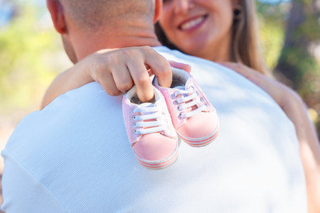 Unrecognizable couple holding pink baby shoes, symbol of love, hope, new life.の写真素材