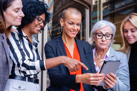 Businesswomen team looking at digital tablet outdoors near office.の写真素材